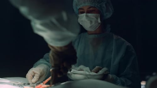 Unknown surgeon hands stitching incision wound medical team suturing in hospital room