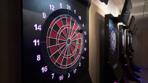 Darts treffen auf die Dartscheibe, nachdem sie von einem Spieler in der Arcade geworfen wurden