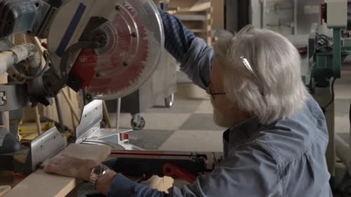 Senior man confidently prepares wood plank with circular saw in community workshop