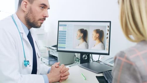 Plastic / Cosmetic Surgeon Consults Woman about Facial Lift Surgery, He Points at Computer Screen S