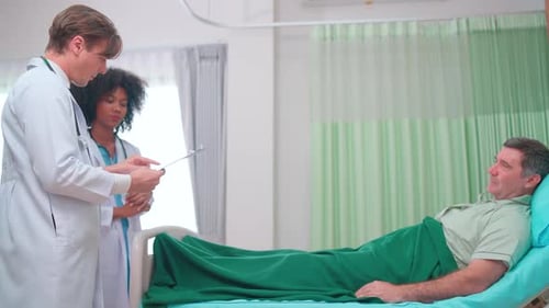 Doctor team use tablet to explain treatment result to senior patient who lie on bed in hospital room