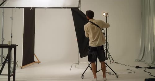 A Confident Brunette Guy a Lighting Master and Cameraman Adjusts the Lights and Spotlights Before