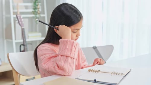 Asian young kid girl struggling with homework in living room at home.