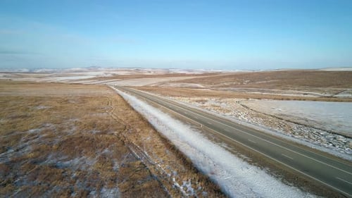 Aerial Orbital Shot of an Intercity Road Surrounded with Snow Covered Fields Winter Landscape