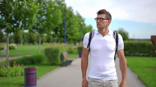 Dolly Shot Portrait of Handsome Confident Caucasian Adult Man Walking in Slow Motion on Park Alley