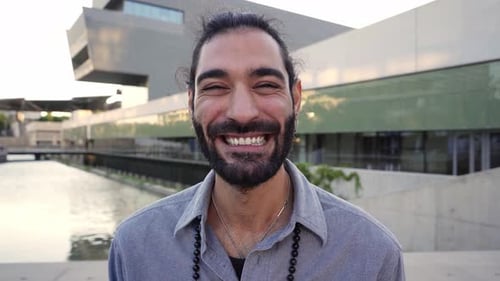 Man with Beard Smiling in Front of Building
