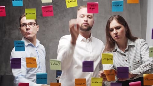Team of Business People is Doing Brainstorm at a Meeting Using Stickers on the Glass Office Workers