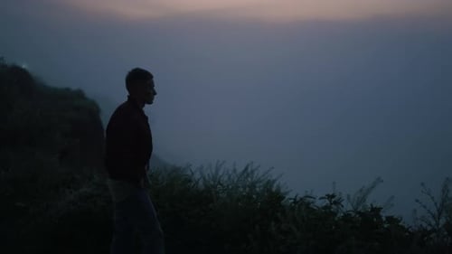 Einsamer Mann, der bei Sonnenaufgang auf dem Berg läuft. Entspannter Typ, der alleine an der Felsenküste steht. Männliches Model...