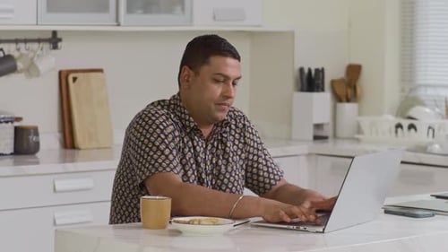 Adult Working At Laptop in Kitchen