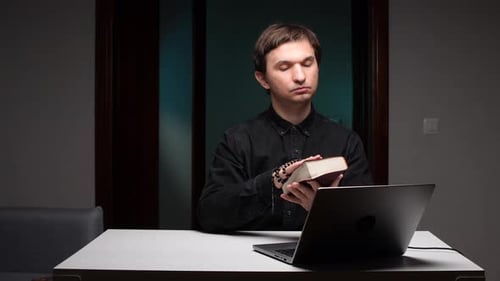 Young Adult Praying at Desk with Rosary