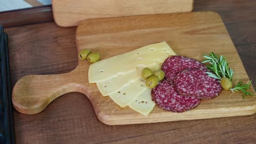 Cutting Board with Salami Cheese and Olives on the Kitchen From Top View