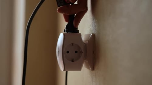Hand plugs Electric Cable into Outlet