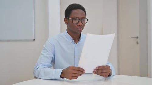 Young Adult Reviews Documents in Corporate Office