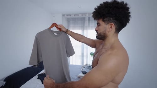 Chico musculoso mirando una camiseta gris