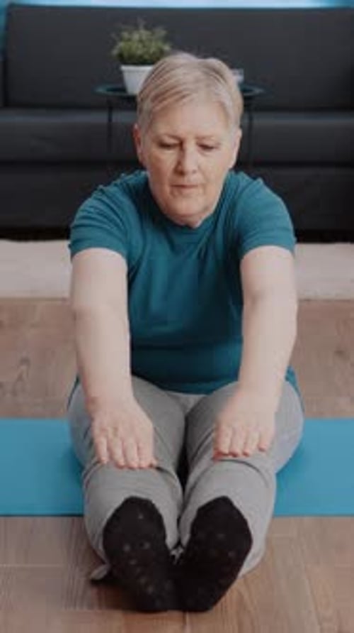 Senior Woman Stretching on Yoga Mat at Home
