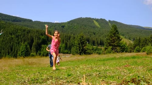 Family Runs Through Field With Kite on Sunny Day