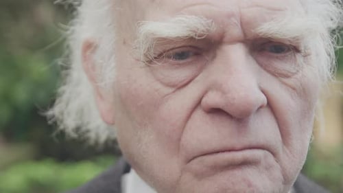 sad old man sitting on bench, close up