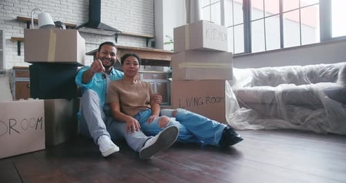 Married Couple Sitting Among Boxes Shows Key to New Flat