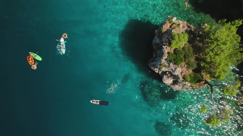 Kayaks and swimmers dot the vibrant blue sea. Leisurely activities blend with natural beauty, aquati