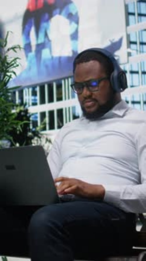 Man Working on Laptop with Headphones Indoors