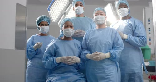 Portrait of diverse surgeons wearing surgical gowns in operating theatre, slow motion