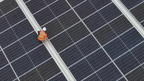 Technician Inspecting Solar Panels from Above on Rooftop