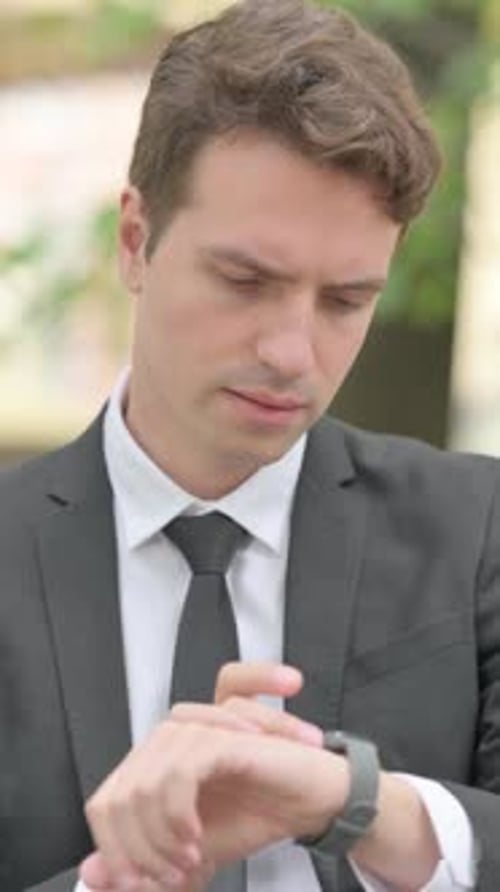 Businessman Checking Smartwatch Outside Wearing Business Suit
