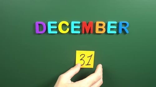 Hand sticking a sticker 31 December calendar day on school board. 31 date of December. Thirty first