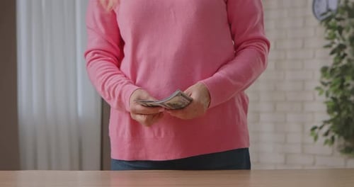Woman counting US Dollar bills inside her home
