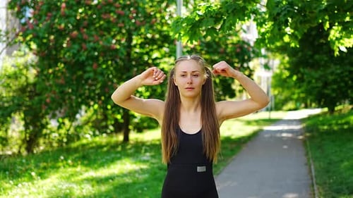 Young Woman in Black Sportswear is Doing Exercise in City Park Warm Up Before Running or Jogging