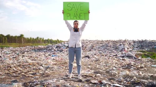 Young Woman Holding Save Planet Sign in Trash Dump