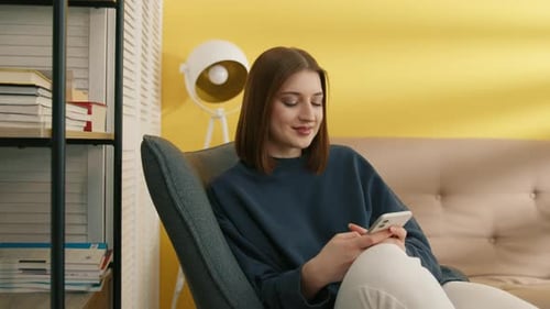 Young Woman Relaxing at Home Using Smartphone