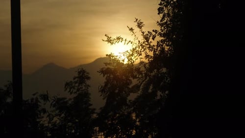 I'm watching the sunset. The sun is setting behind the mountains in the distance on the sea.