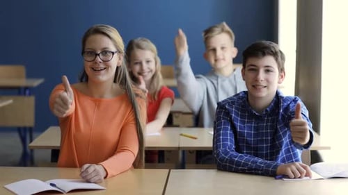 Students Sitting at Desks Giving Thumbs Up