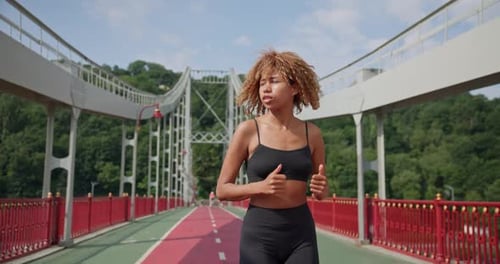 Young African American Woman Runner Jogging on City Bridge Outdoors