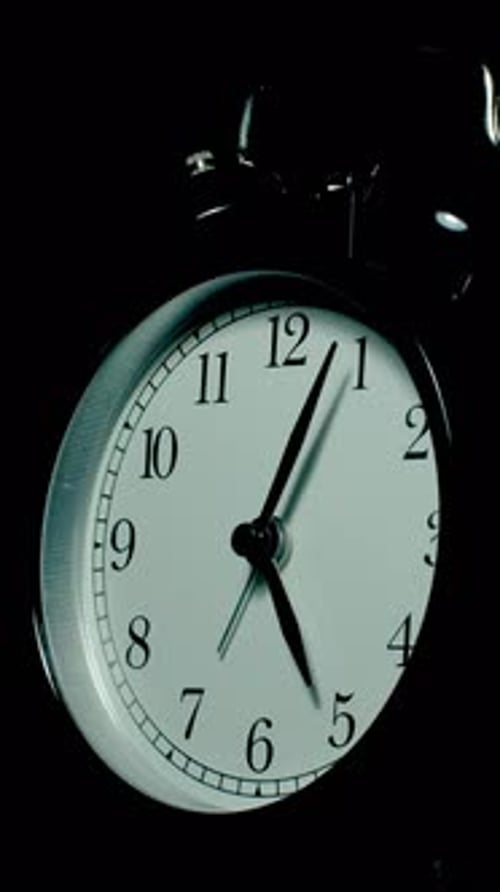 Vidéo en accéléré vertical d'une horloge passant du jour à la nuit sur fond noir.