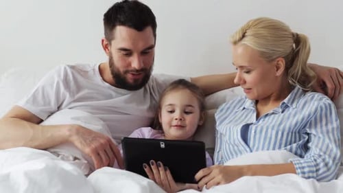 Happy Family Using Tablet Device in Bed