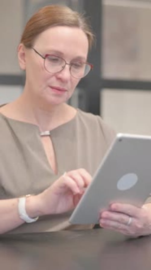 Old Businesswoman Doing Video Chat on Tablet in Office