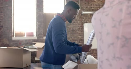 Diverse colleagues packing boxes with documents and office items in creative office in slow motion