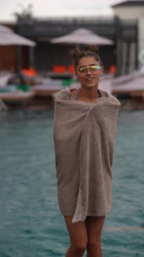 Undeterred By the Rain a Radiant Young Girl in a Towel and Bathing Suit Dances By the Pool