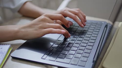 Woman Typing on Laptop Keyboard in Office