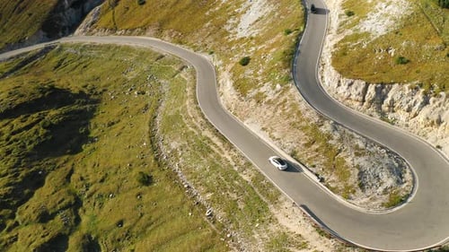 Cars Drive on Asphalt Highway Curve in High Italian Alps