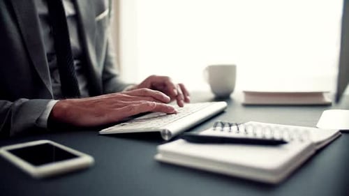 Man in suit types on computer keyboard indoors