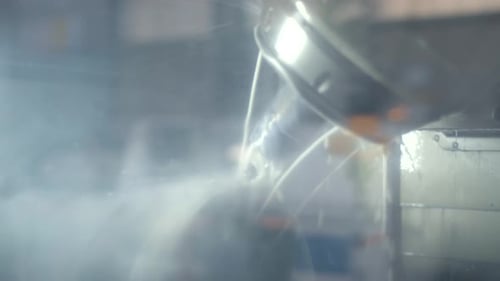 Cnc automated cutter working on a rotating piece of steel lubricated with water