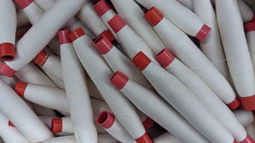 Close-Up of White Thread Spools with Red Caps