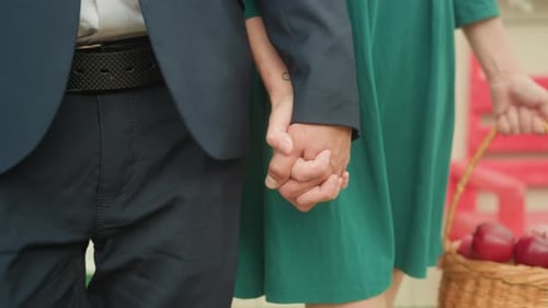 Loving Couple Holding Hands Outside with Basket of Apples