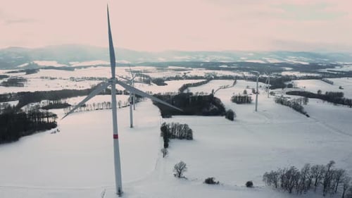 Wind Turbines That Produce Electricity in the Winter Field at Sunset