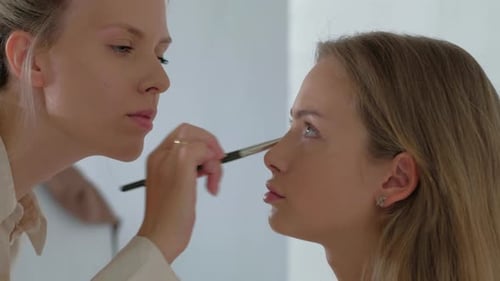 Young Makeup Artist Doing Makeover To Pretty Model