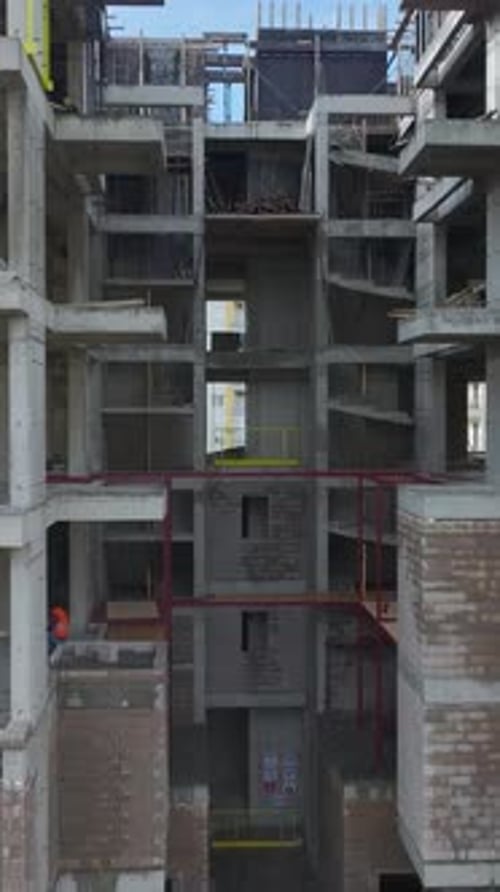 Vertical Video Construction of a HighRise Building With Cranes Scaffolding and Workers Captured