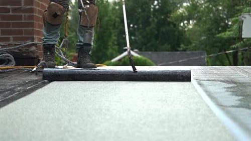 Roofer Smoothing Out Silver Flat Roof
